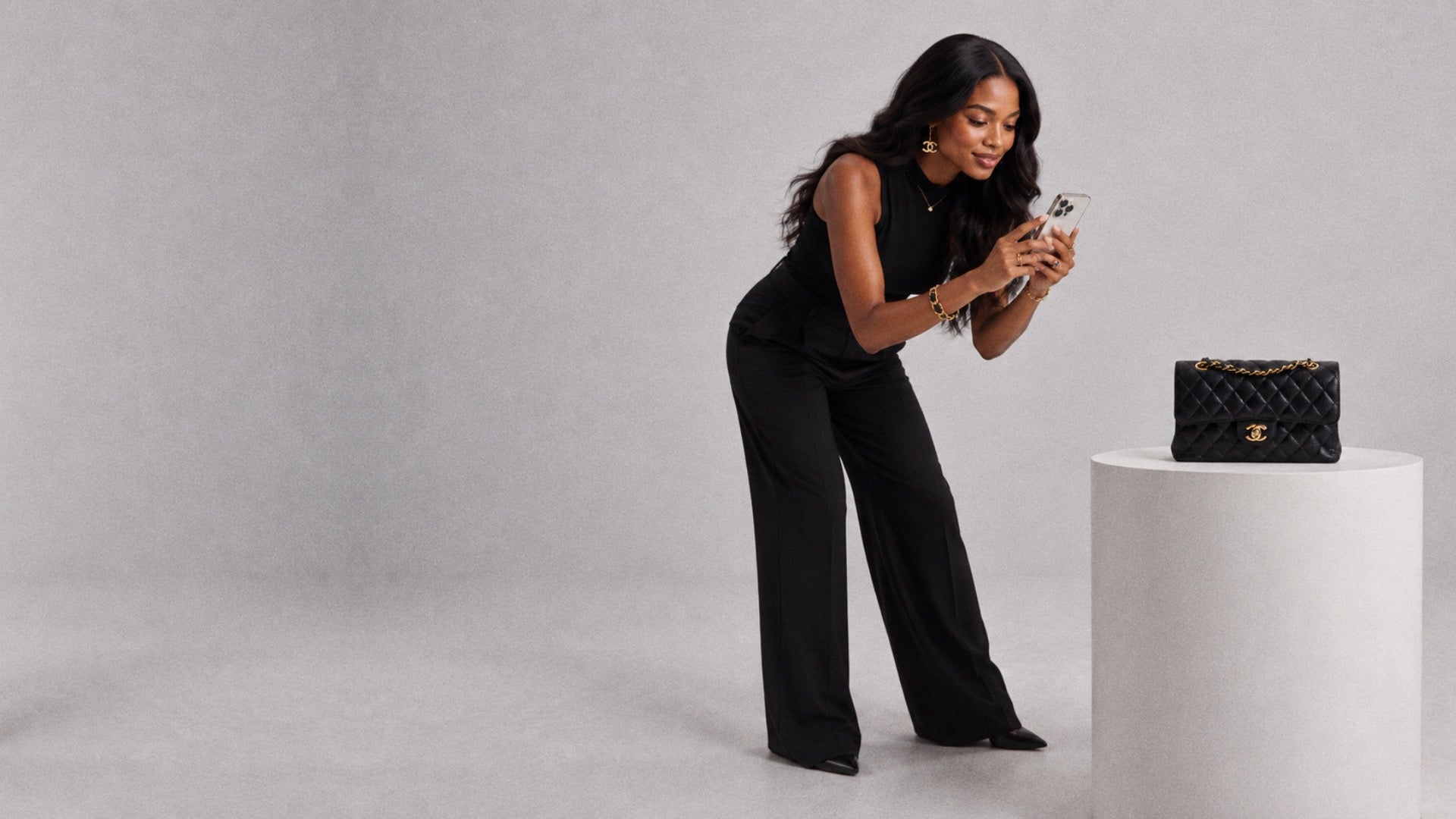 A woman photographing a Chanel bag with her phone